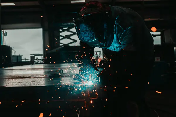Soldador trabajando en un taller metalúrgico.
